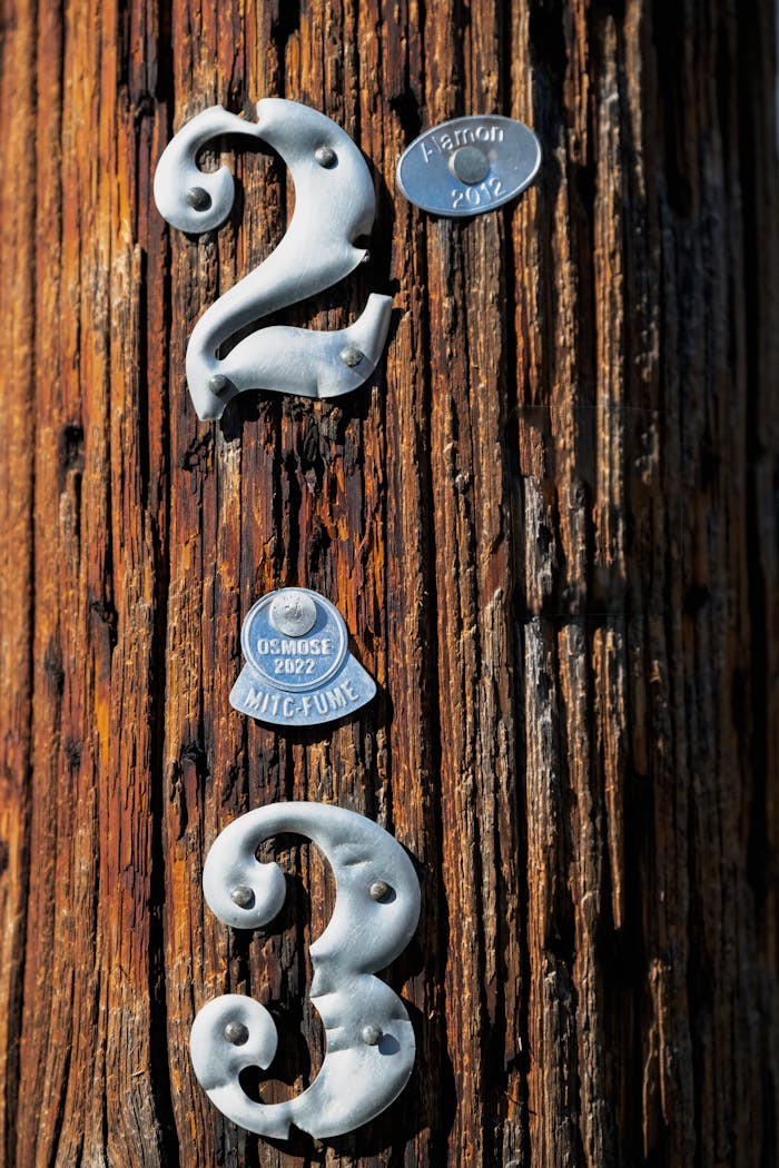 Detailed view of metal numbers 2 and 3 on a wooden pole with plaques.