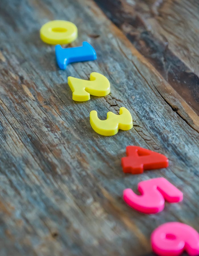 Bright plastic numbers arranged on rustic wood background for educational concept.